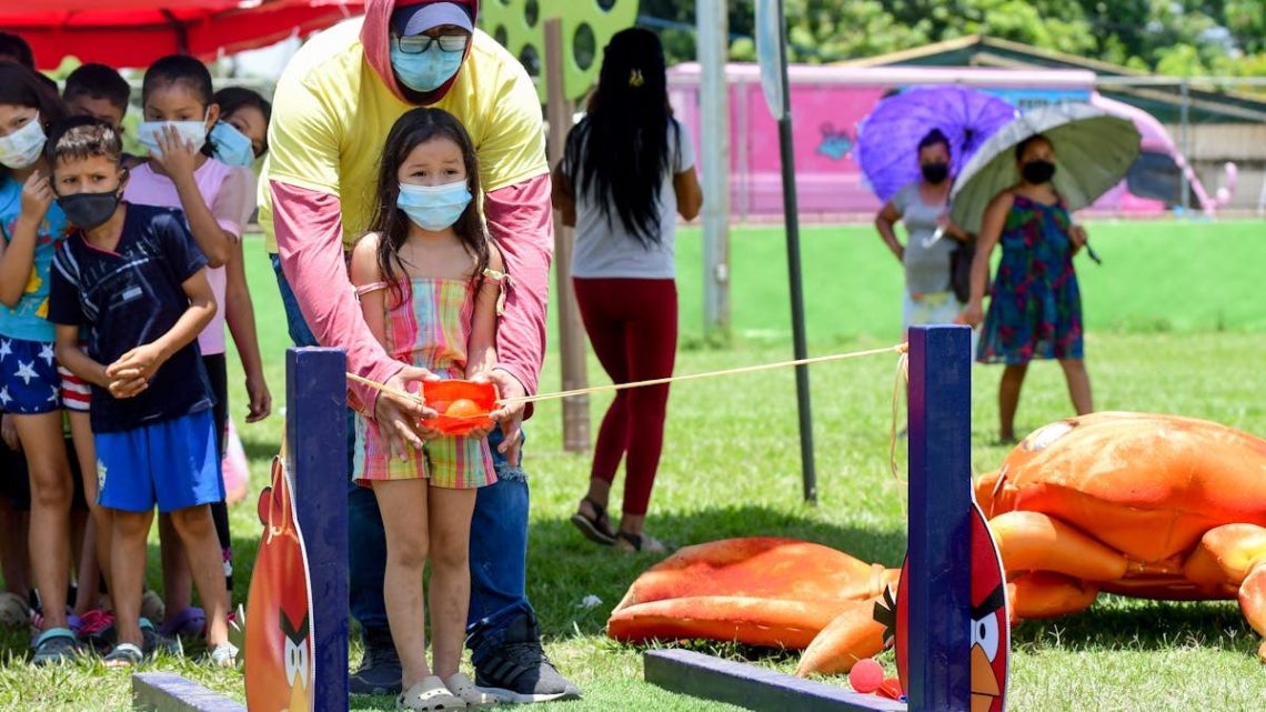Children enjoying an outdoor game event while wearing face masks for safety.